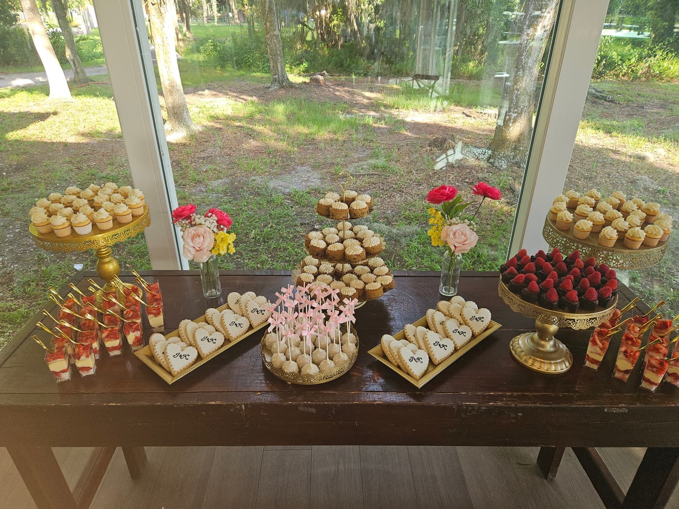 Wedding dessert table with mini cupcakes, cake pops, dessert shooters and monogram heart cookies on gold stands
