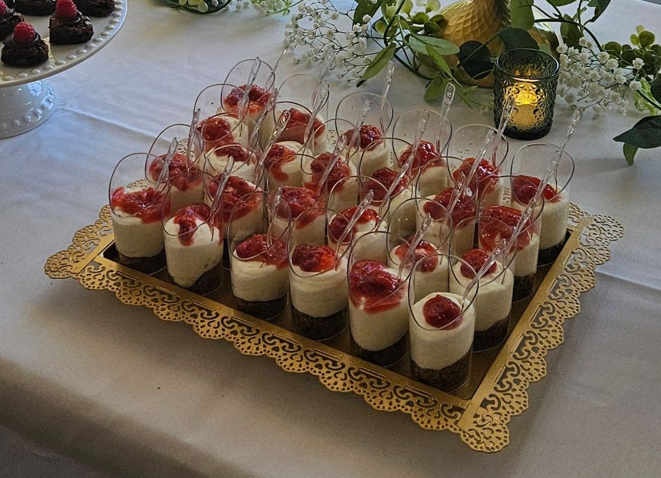 Dessert shooters layered with cream and strawberry on a gold tray