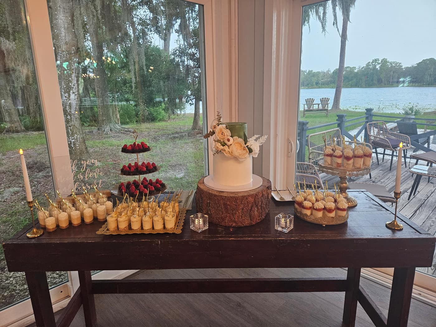 Lakeside dessert table at dusk with a one tier cake, dessert shooters and candles