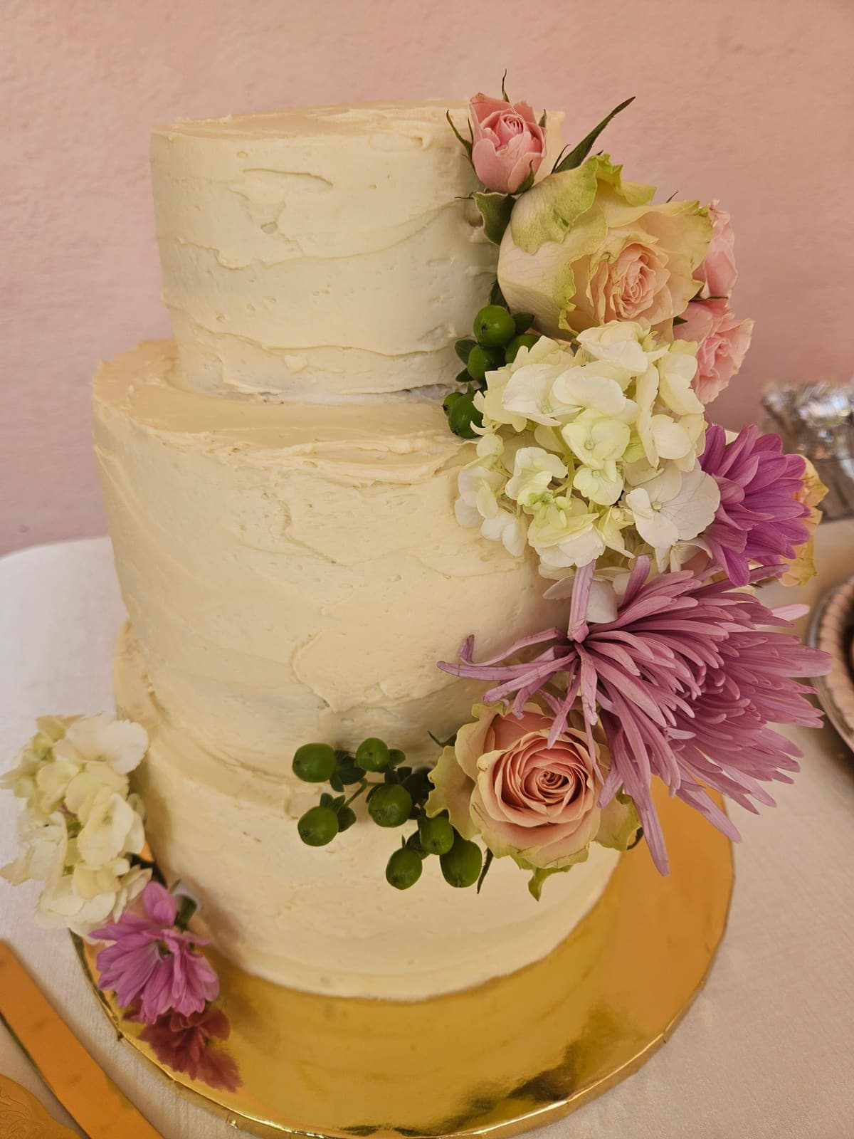 Two tier textured buttercream cake with fresh roses, hydrangea and lilac mums