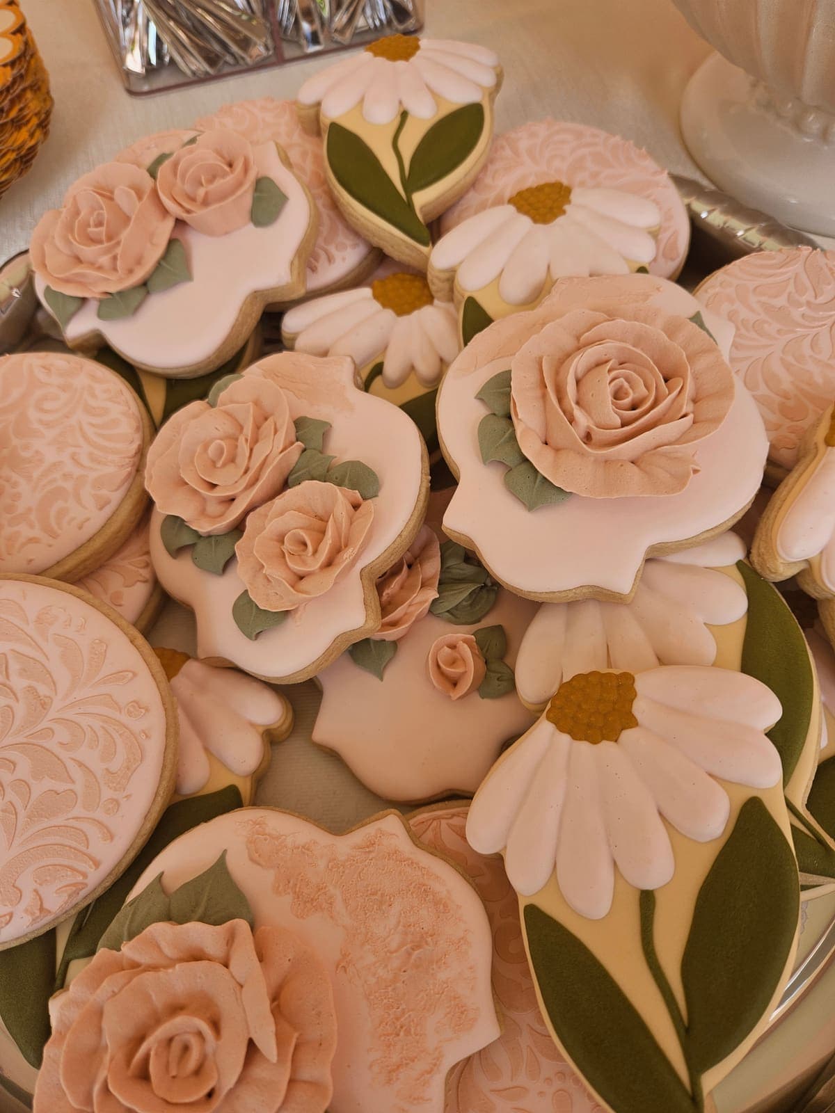 Sugar cookies decorated with piped blush roses, daisies and lace patterns