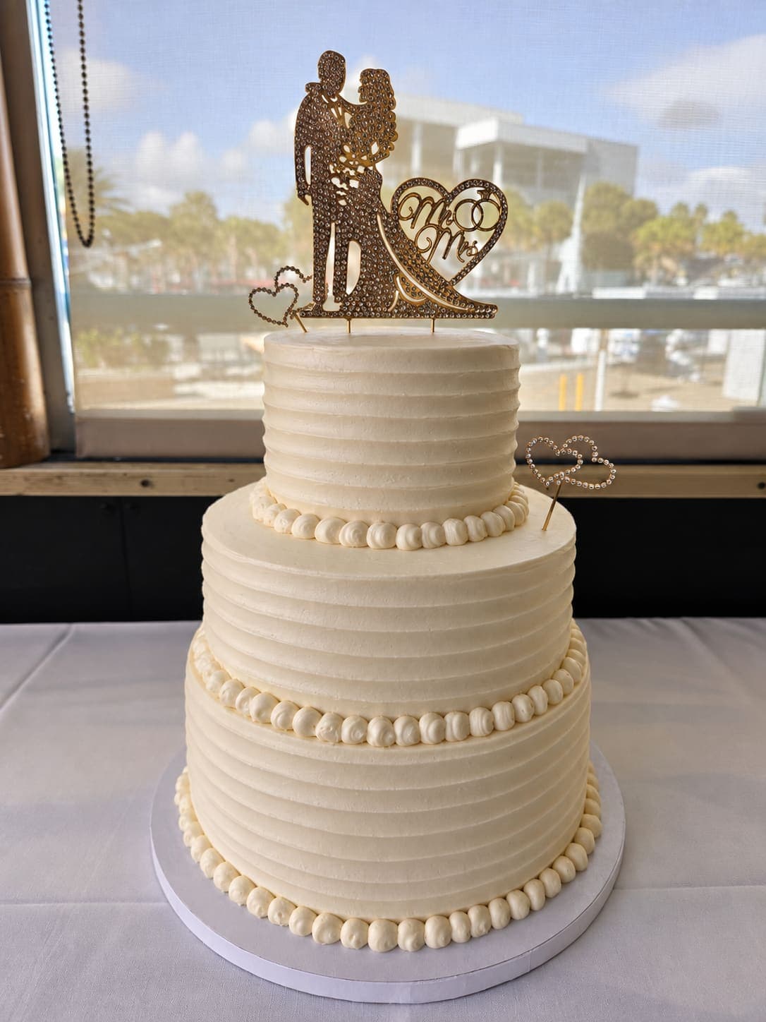 Three tier ribbed buttercream wedding cake with piped pearl borders and a gold Mr and Mrs topper