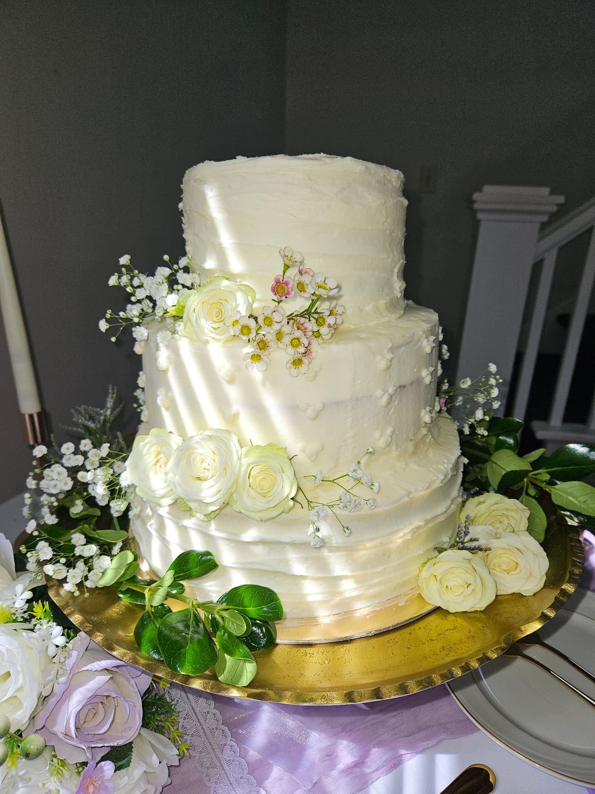 Three-tier white buttercream wedding cake with cream roses and baby's breath